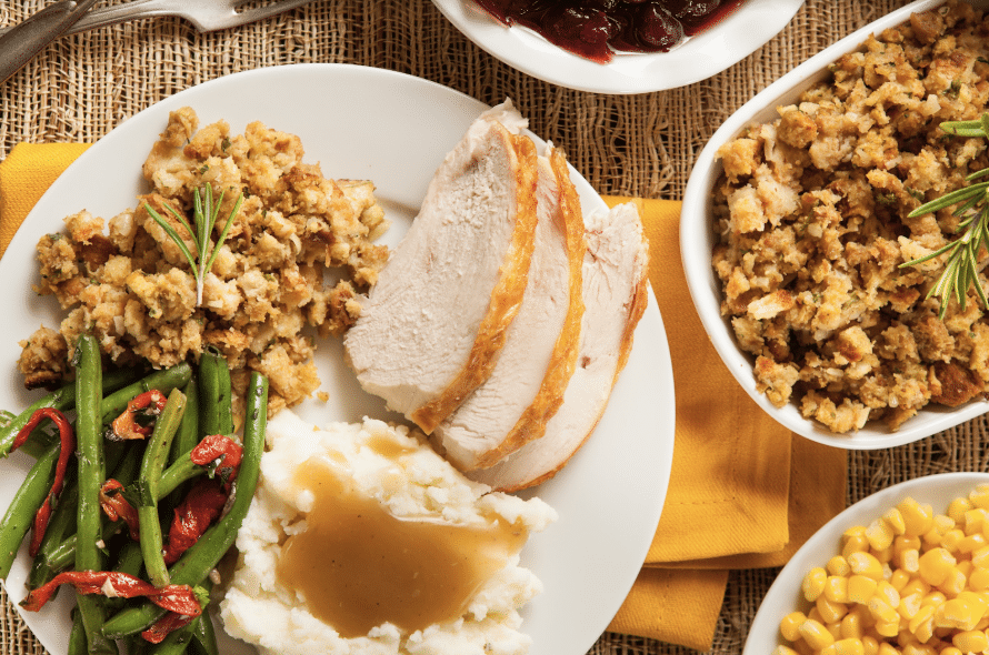 Photo of a Thanksgiving dinner plate with beans, stuffing, mashed potatoes, and turkey.