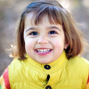 a little girl with a yellow rain jacket smiling up at the camera