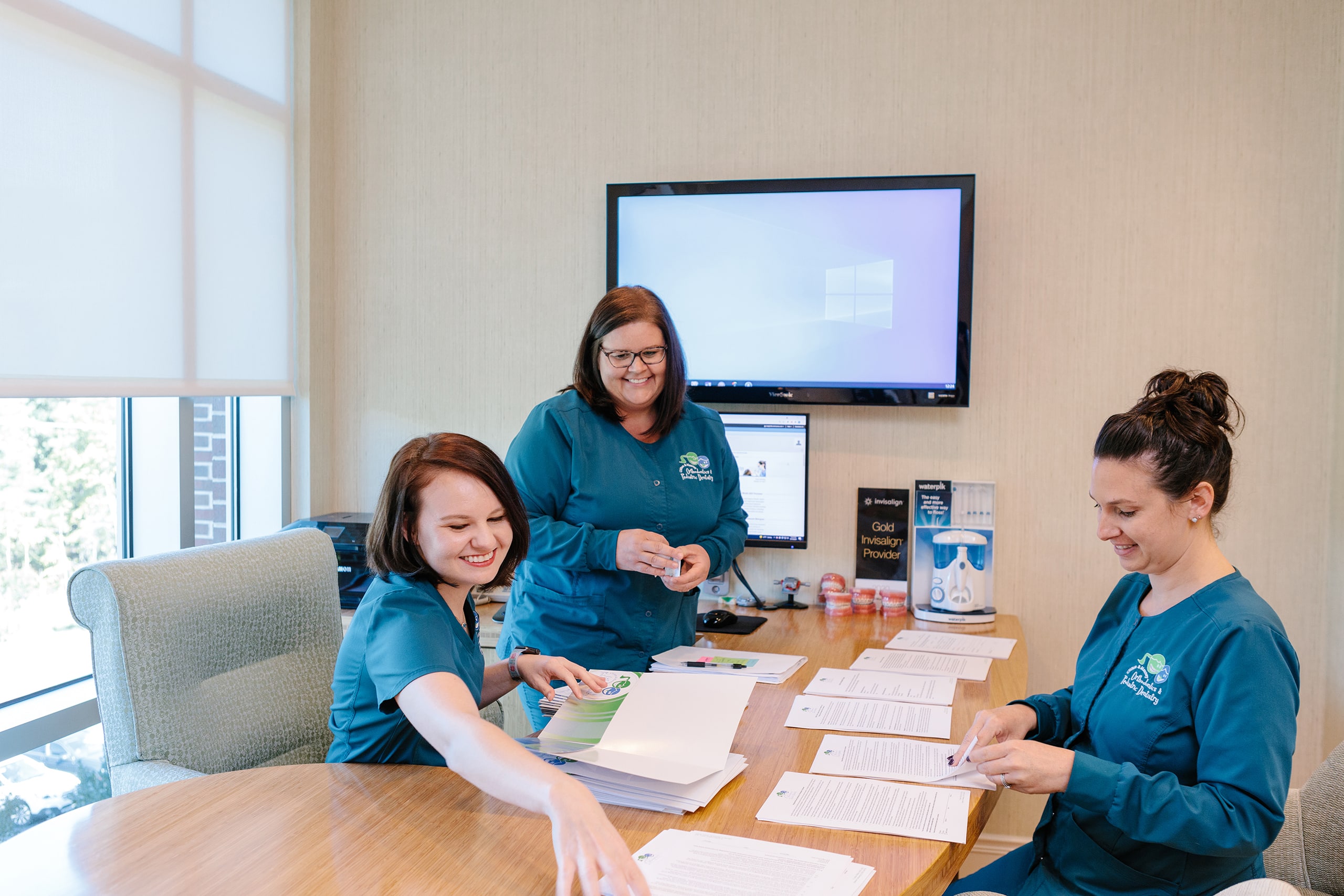 Two orthodontist assistant filing paperwork at a desk.