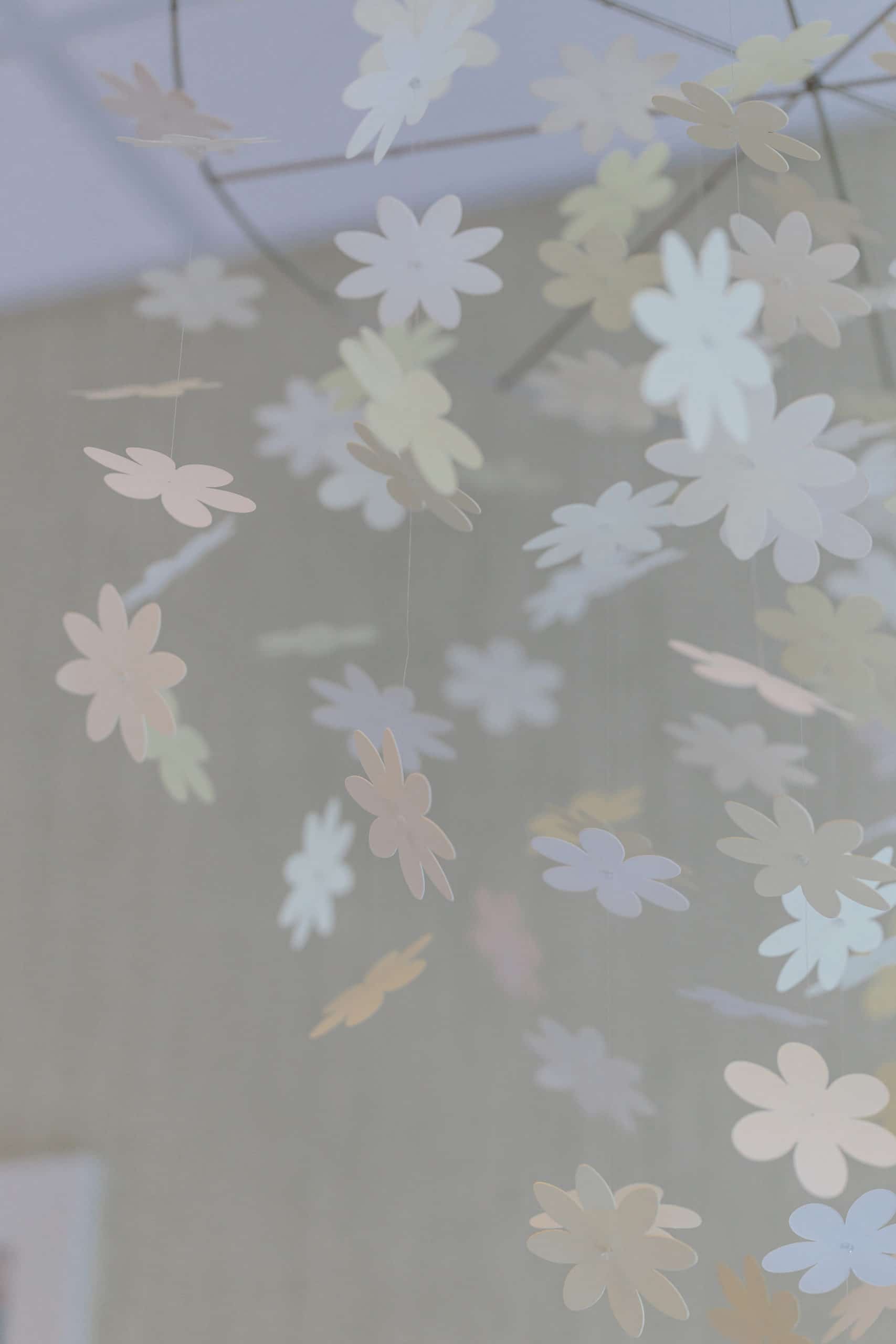A faded photo of a mobile with paper flower cutouts.