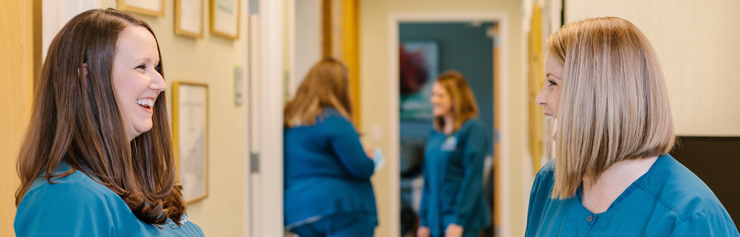 Our team at clifton & mauney smiling at each other as they chat in a hallway at our Chapel Hill office