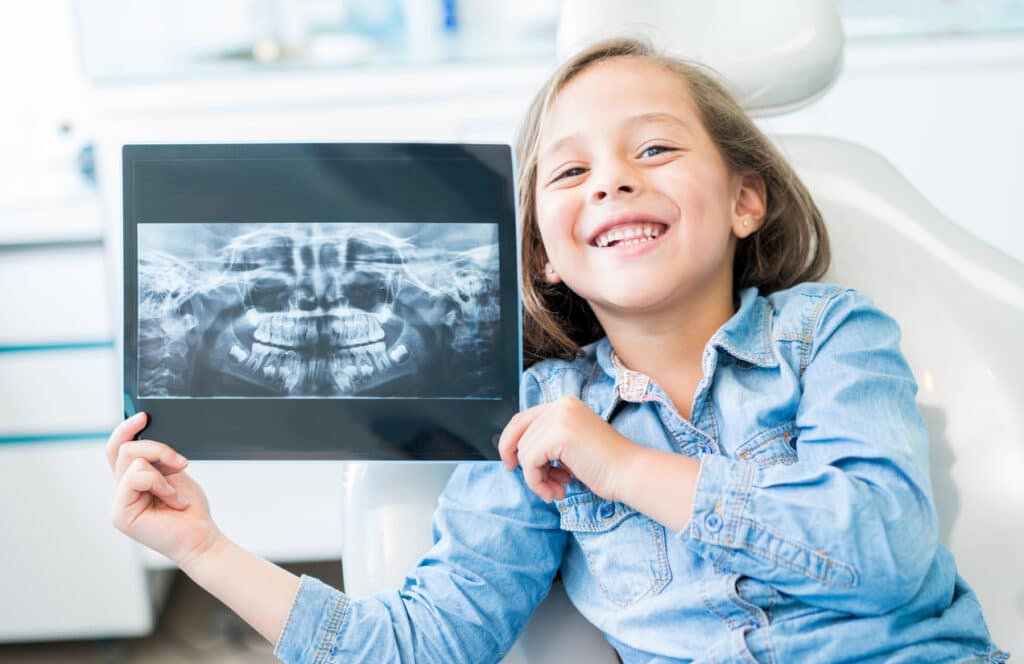 a child at the orthodontist holding up her dental x rays