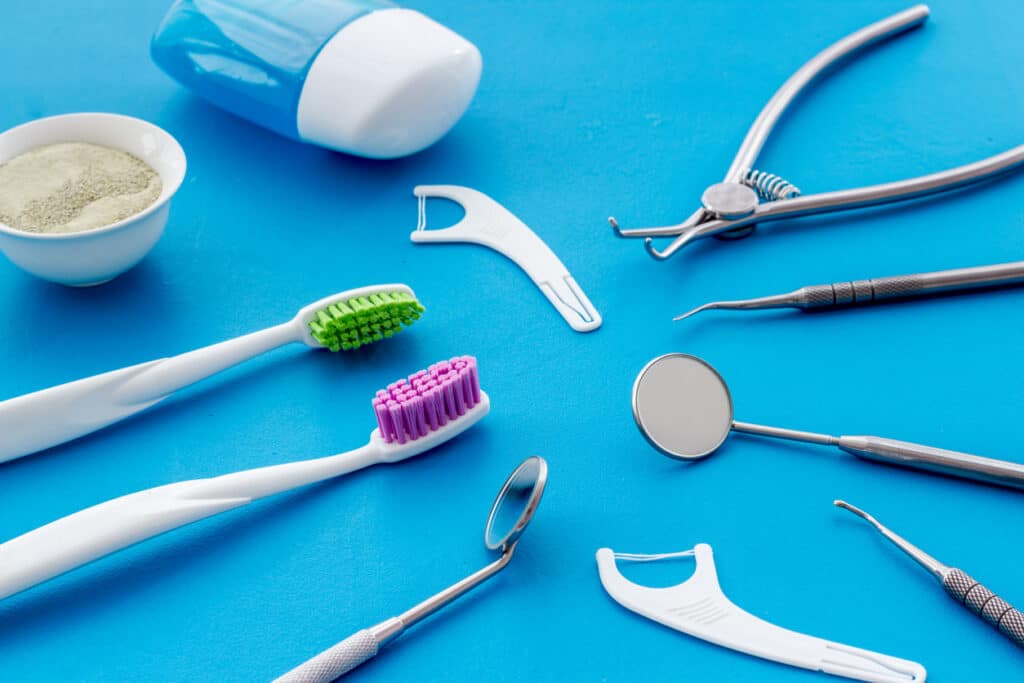 various orthodontic cleaning tools such as floss, toothbrush, and pick on top of a blue table