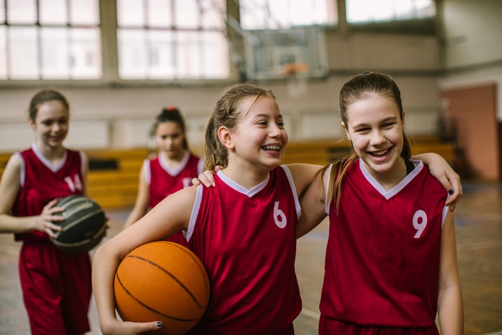 a group of young girls with braces playing basketball at the gym