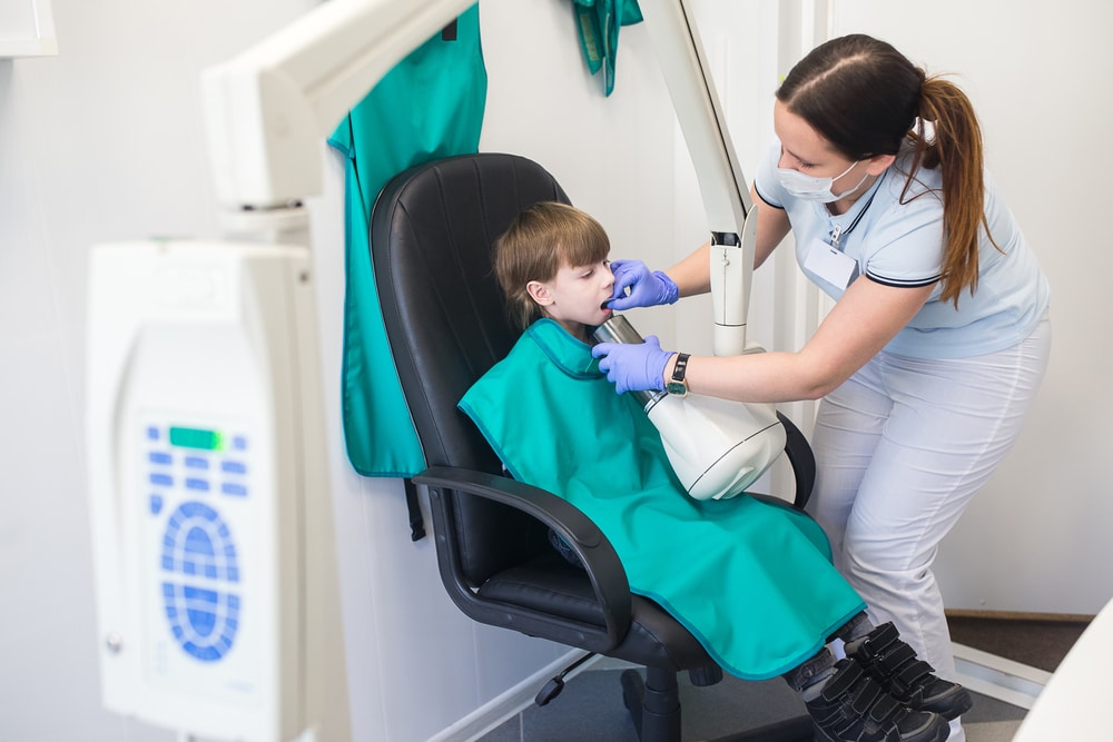 a young child getting dental x rays by an orthodontic assistant