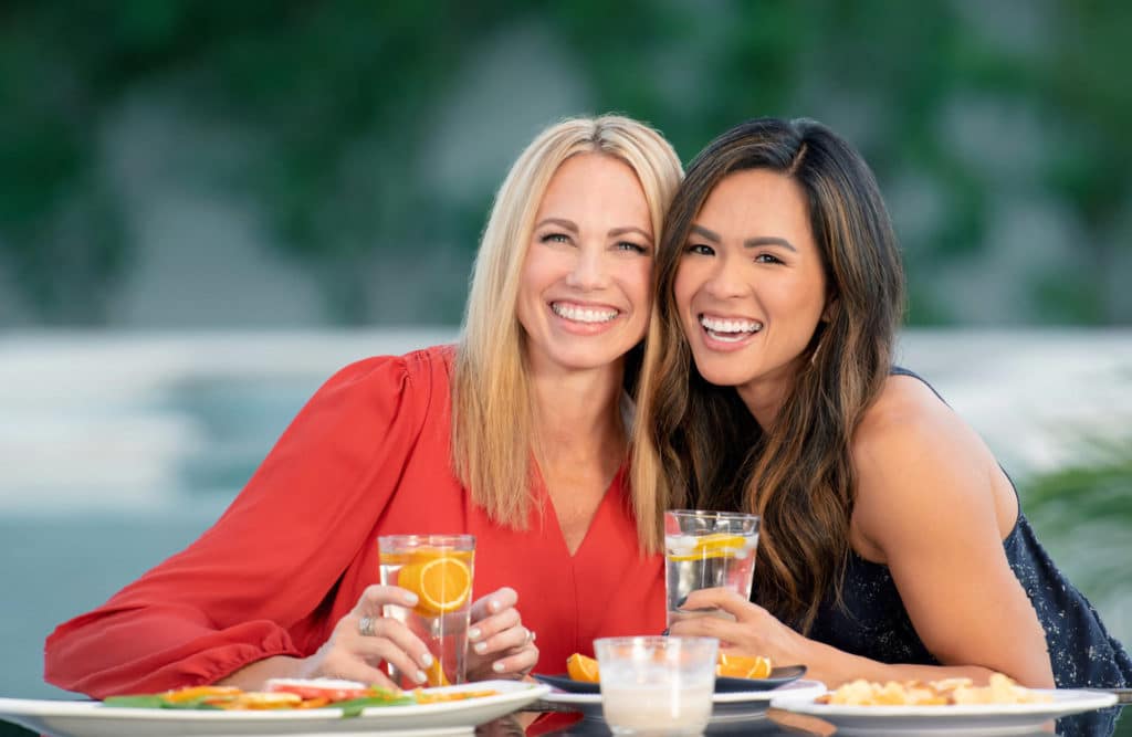 two woman smiling to show their nearly invisible clear aligners while getting drinks