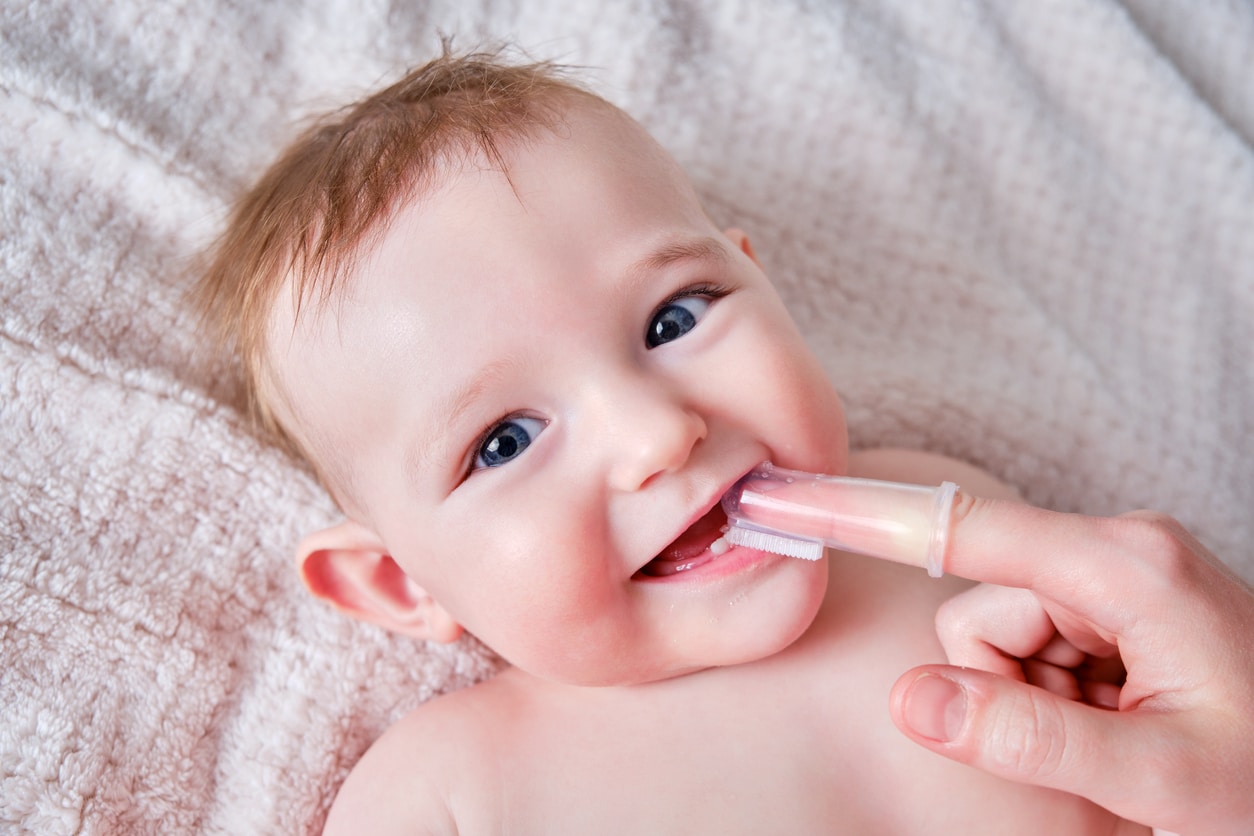 a mom brushing her baby's mouth with a baby finger toothbrush