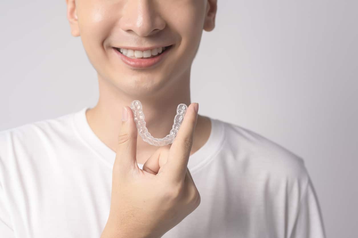 a teenage patient holding invisalign clear aligners up