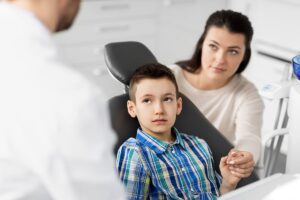 Child looks at dentist with worry as he learns about common types of dental trauma