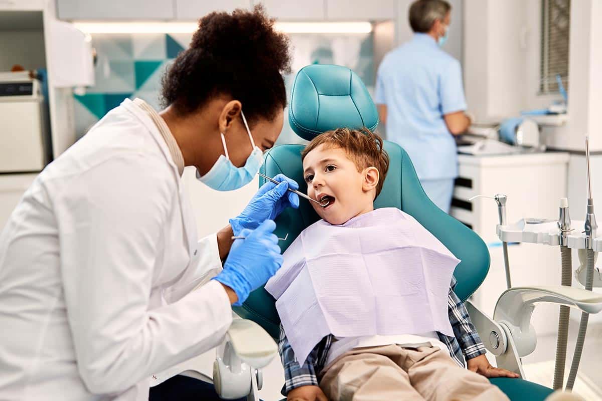 a child is having their teeth checked after getting pediatric crowns at the dentist