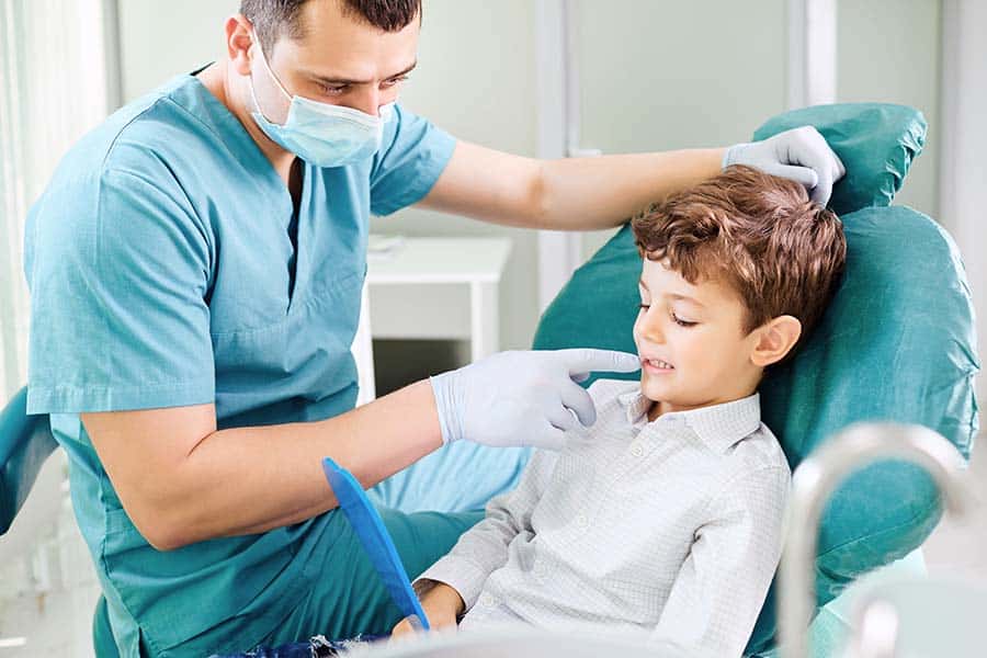 little boy looking in the mirror at the dentist