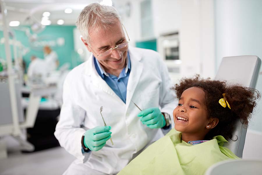 little girl sitting in dentist chair after her parent filled out patient forms