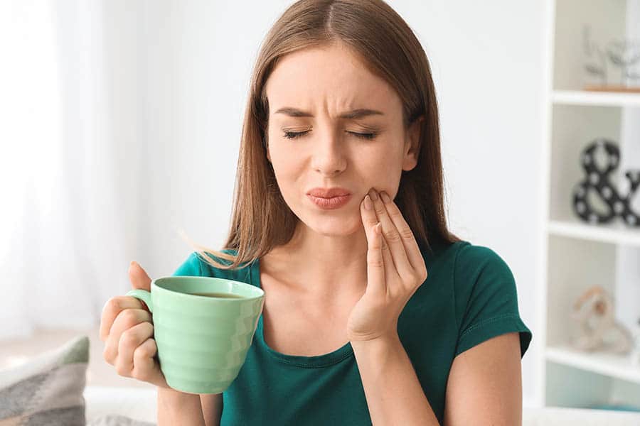 a woman suffering from tooth sensitivity which is a common tooth problem