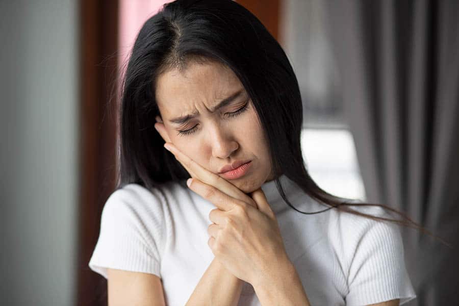 woman dealing with a tooth ache, a common tooth problem