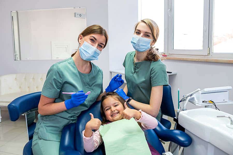 a little girl giving a thumbs up having fun at the dentist