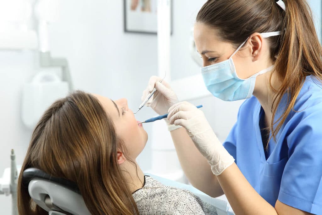 a teen patient gets her teeth cleaned at the dentist