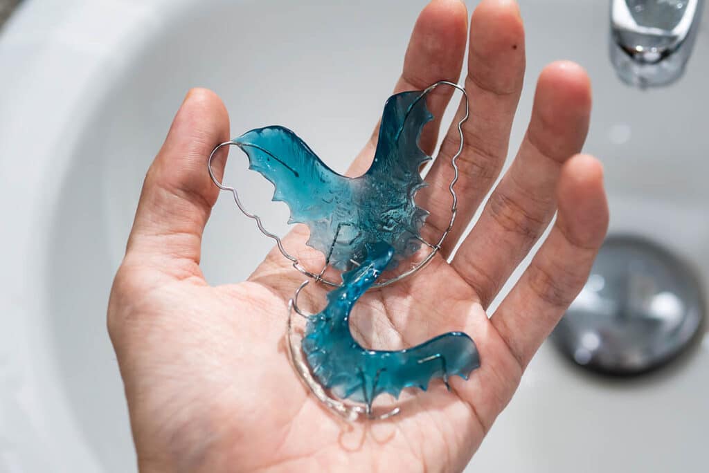 a teen cleans their retainers in the sink