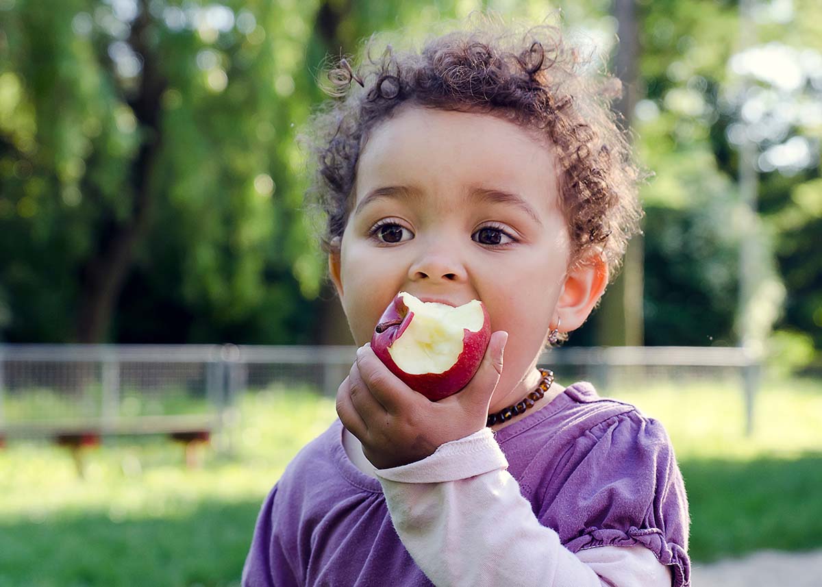 a child eats an apple in the park