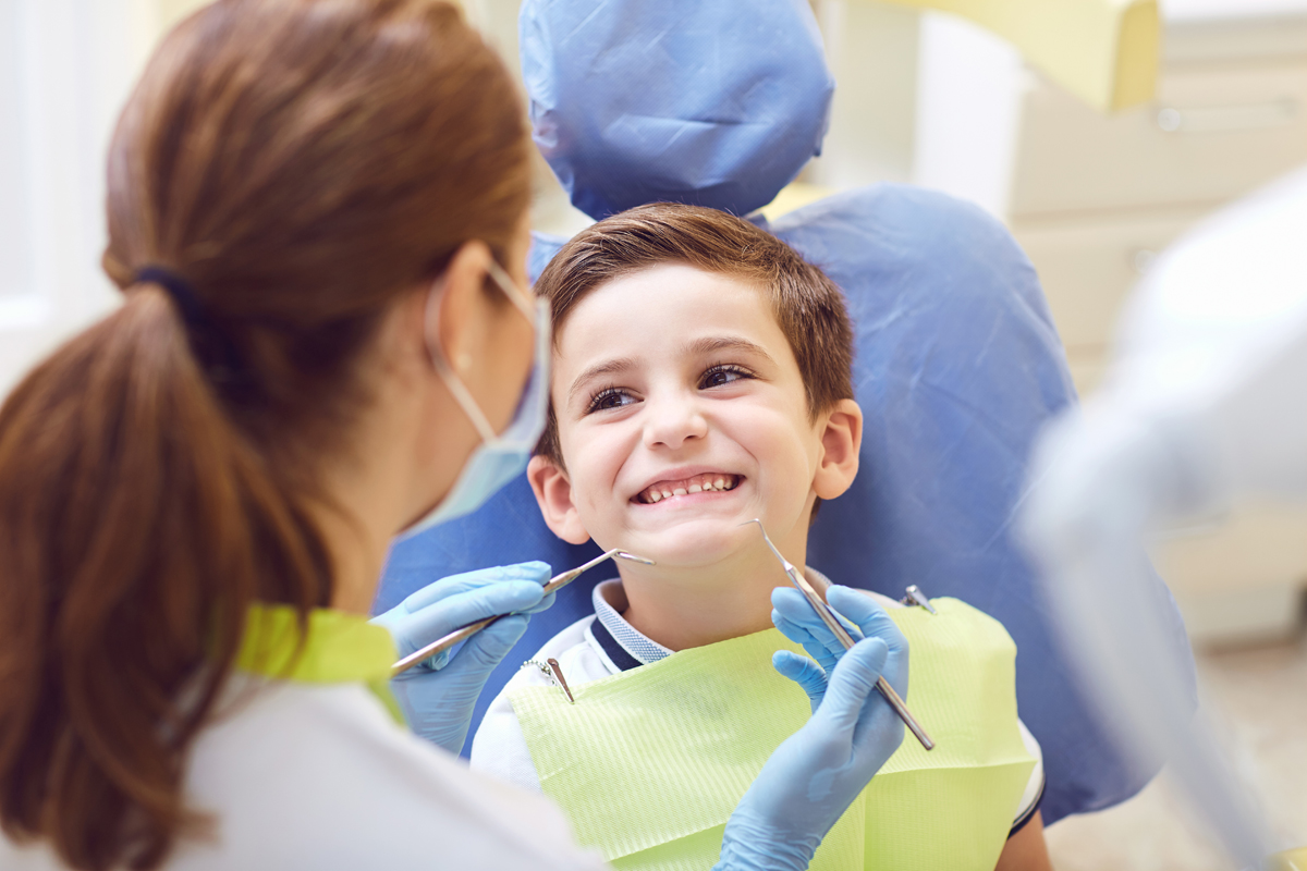 Dental hygienist with boy in dentist's chair